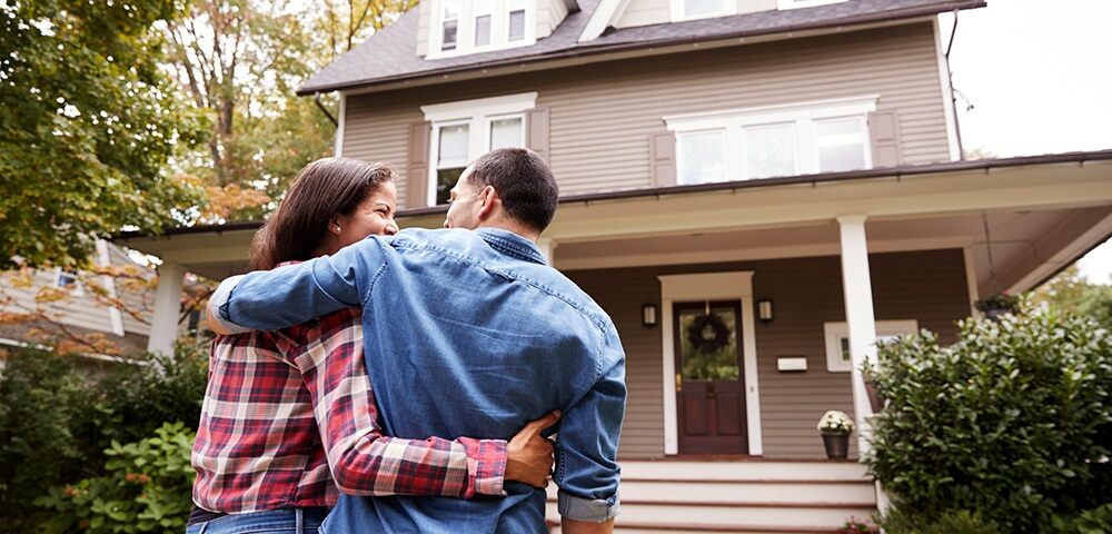 embracing couple walking into their new home
